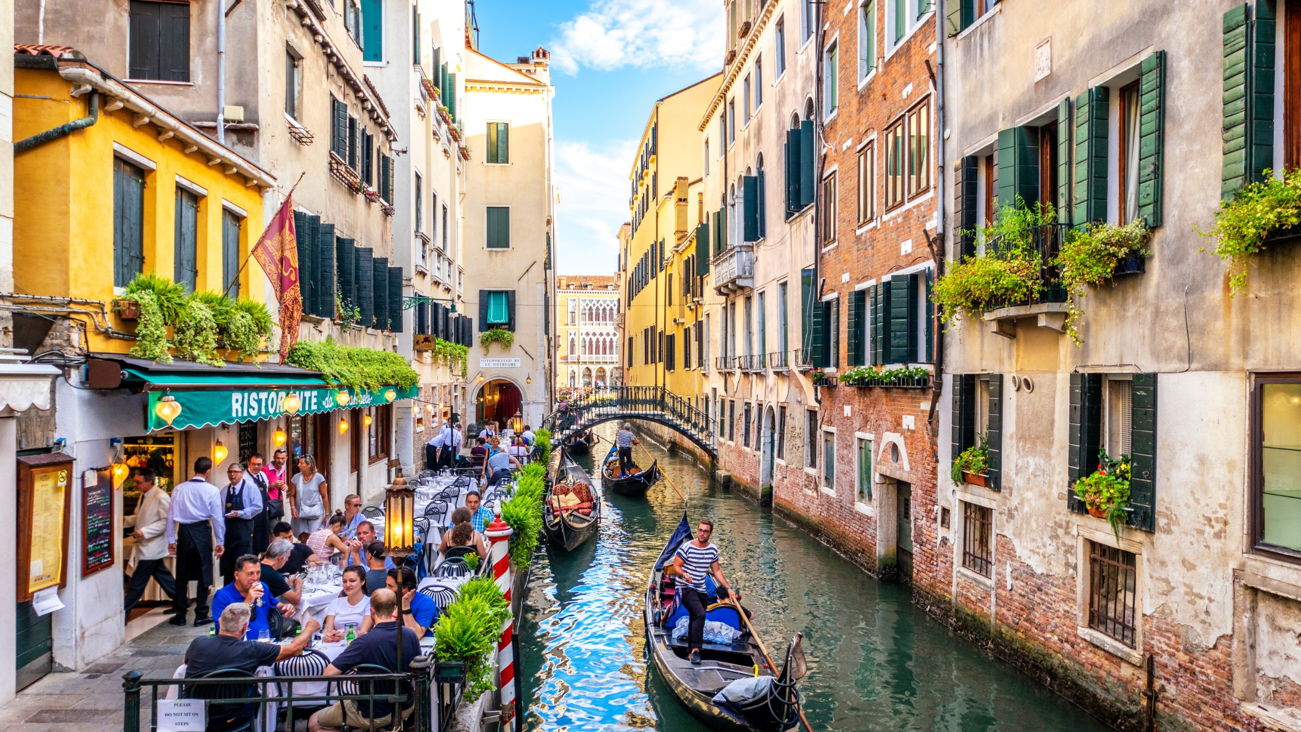 Gondola cruising along in the Venetian Canals with solo tourists enjoying the sights together.